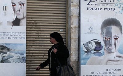 A woman walks past a vandalized poster in Jerusalem, December 6, 2011. (photo credit: Yossi Zamir/Flash90)