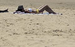Illustrative photo of a beach in Ashdod. Beach-goers like this woman will hopefully be able to relax more easily now that the robbery ring has been broken up by a local ice cream kiosk owner. (photo credit: Tsafrir Abayov/Flash90)