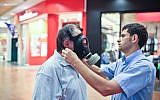 A man tries out a gas mask at an Israeli distribution center (photo credit: Noam Moskowitz/Flash90/File)
