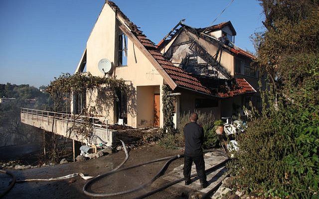 A firefighter tries to extinguish a house that was burned down in a major forest fire raging in Tivon on Thursday, August 09 (photo credit: Avishag Shaar Yashuv/Flash90)