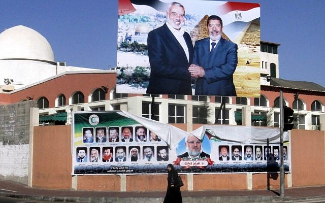 A Palestinian woman walks past a poster of Gaza's Hamas Prime Minister Ismail Haniyeh, left, and Egyptian President Mohammed Morsi in Gaza City, in August (photo credit: AP)