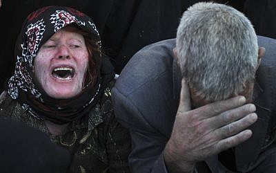 An Iranian woman and a man grieve after their loved ones were killed during Saturday's earthquake at the village of Bajebaj near the city of Varzaqan in northwestern Iran, on Sunday. (photo credit: AP/ISNA, Arash Khamoushi)