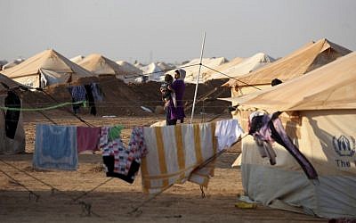 A Syrian refugee plays with her child in front of her family's tent in the Zaatari Syrian Refugee camp, in Mafraq, Jordan. (photo credit: Mohammad Hannon/AP)