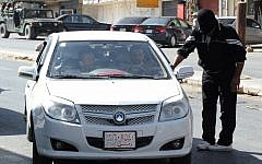 A masked man from a Sunni group who blocked a road linked to the Lebanese-Syrian border, checks a Syrian car which carries Syrian passengers, in Masnaa, eastern Lebanon, in August 2012. (photo credit: AP photo)
