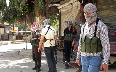 Rebels gather on a corner during fighting with Syrian troops in a suburb of Damascus, Syria (photo credit: AP/File/Mohammad Hannon)