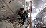 Syrian fighters search for survivors under the rubble of a building destroyed in an airstrike in Aleppo, August 17 (photo credit: AP/Khalil Hamra)