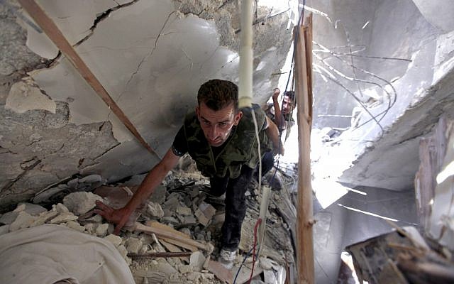 Syrian fighters search for survivors under the rubble of a building destroyed in an airstrike in Aleppo, August 17 (photo credit: AP/Khalil Hamra)