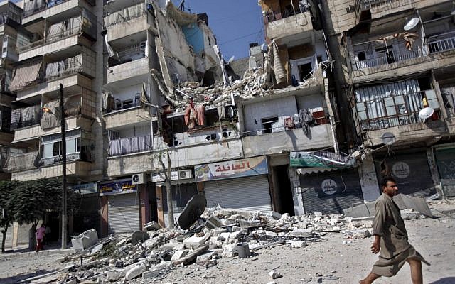 A Syrian man walks by a building destroyed in an airstrike in Aleppo, Syria, on Friday, Aug. 17, 2012. (photo credit: Khalil Hamra/AP) A Syrian man walks by a building destroyed in an airstrike in Aleppo, Syria, on Friday, Aug. 17, 2012. (photo credit: Khalil Hamra/AP)