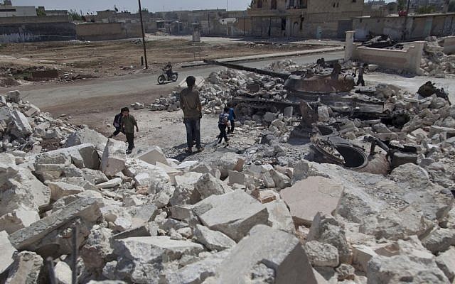 Syrian children play near a destroyed military tank next to the rubble of a damaged building in town of Azaz on the outskirts of Aleppo, Syria on Wednesday (photo credit: AP/Khalil Hamra) Syrian children play near a destroyed military tank next to the rubble of a damaged building in town of Azaz on the outskirts of Aleppo, Syria on Wednesday (photo credit: AP/Khalil Hamra)