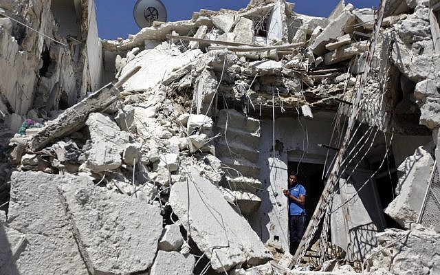 A Syrian man looks out of the rubble as rescuers, not shown, look for the bodies of two girls thought to be under the rubble of a building hit by a Syrian government airstrike in Aleppo in August 2012 (photo credit: AP/Khalil Hamra) A Syrian man looks out of the rubble as rescuers, not shown, look for the bodies of two girls thought to be under the rubble of a building hit by a Syrian government airstrike in Aleppo in August 2012 (photo credit: AP/Khalil Hamra)