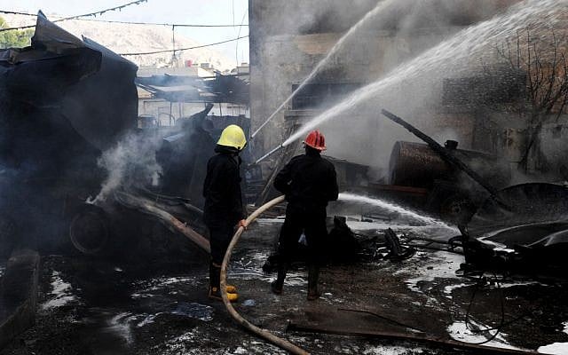 Firefighters extinguish fire at the scene after a bomb attached to a fuel truck exploded outside a Damascus hotel in August (illustrative photo credit: AP/SANA)