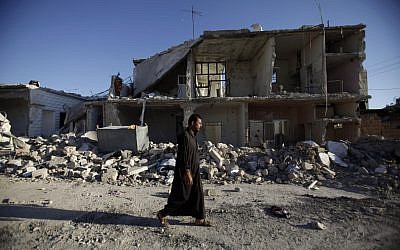 A man walks by a destroyed building in Azaz near Aleppo last week. (photo credit: AP/Muhammed Muheisen)