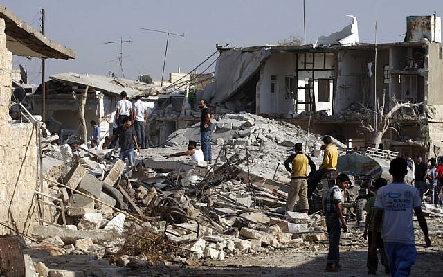 Syrians check the damage of destroyed houses after an air strike destroyed at least ten houses in the town of Azaz on the outskirts of Aleppo, Syria on Wednesday (photo credit: AP/Khalil Hamra) Syrians check the damage of destroyed houses after an air strike destroyed at least ten houses in the town of Azaz on the outskirts of Aleppo, Syria on Wednesday (photo credit: AP/Khalil Hamra)