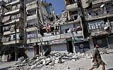 A Syrian man walks by a building destroyed in an airstrike in Aleppo, August 17 (photo credit: AP/Khalil Hamra)