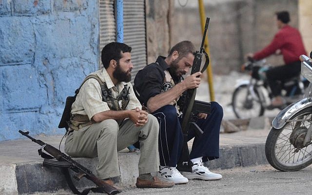 Free Syrian Army soldiers sit on a sidewalk in the northern town of Sarmada, in Idlib province, Syria, in August (photo credit: AP Photo)