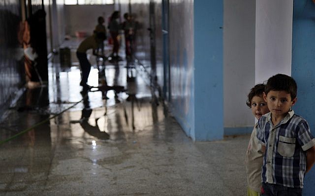 Syrian children clean a school in which they sought refuge from the fighting in Kafr Hama (six miles north of Aleppo) on Tuesday (photo credit: AP/Khalil Hamra)