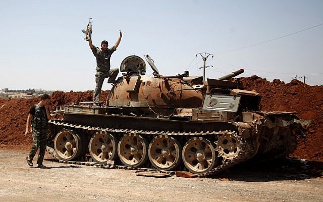 A Free Syria Army fighter waves from the top of a destroyed army tank in Syria, Monday, Aug. 6, 2012. (photo credit: AP) A Free Syria Army fighter waves from the top of a destroyed army tank in Syria, Monday, Aug. 6, 2012. (photo credit: AP)