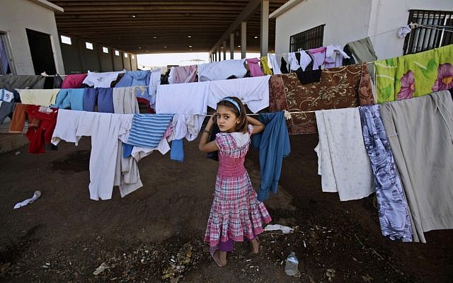 A Syrian girl who fled her home with her family checks her laundry as she and others take refuge at the Bab Al-Salameh border crossing with Turkey, near the Syrian town of Azaz, on Sunday, Aug. 26, 2012. (photo credit: Muhammed Muheisen,/AP