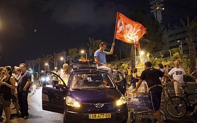 A demonstrator waves a flag at one of two protests Saturday night in Tel Aviv (photo credit: Tali Mayer /Flash90)