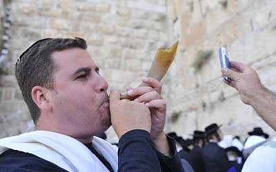 A man uses his cellphone to transmit the blowing of the shofar at the Western Wall. (photo credit: Serge Attal/Flash90)