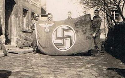 The author's father, Private Alexander Breuer (left), holding a Nazi flag he captured with his comrades in a small German town (photo credit: courtesy Heddy Abramowitz)