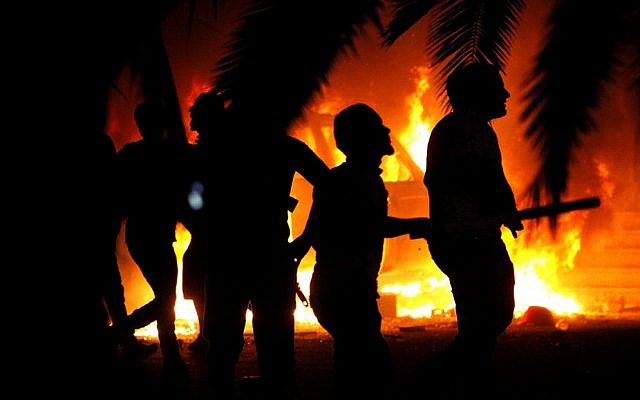 Libyan civilians watch fires in Ansar al-Shariah Brigades compound, after hundreds raided the Brigades base, in Benghazi, Libya, Friday, Sept. 21 (photo credit: AP/Mohammad Hannon)