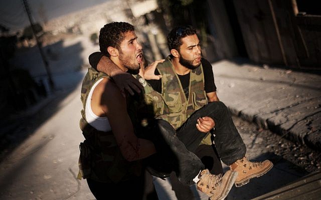 Two Free Syrian Army fighter evacuate a wounded comrade in Aleppo, September 7 (photo credit: AP/Manu Brabo)