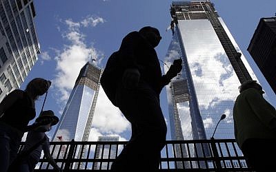 Visitors to the National September 11 Memorial walk below the rising towers 1 World Trade Center, left, and 4 World Trade Center. Wednesday marks the twelfth anniversary of the attacks of Sept. 11, 2001. (Mark Lennihan/AP)