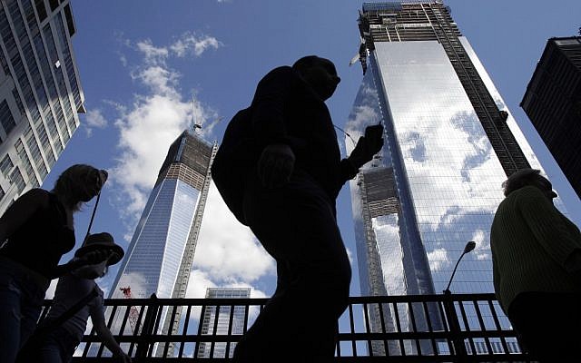 Visitors to the National September 11 Memorial walk below the rising towers 1 World Trade Center, left, and 4 World Trade Center. Wednesday marks the twelfth anniversary of the attacks of Sept. 11, 2001. (Mark Lennihan/AP)