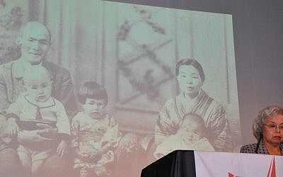 Tsuchida Kazumi, with a photo of her family behind her, speaking in Tel Aviv Wednesday (photo credit: Michal Shmulovich/Times of Israel)