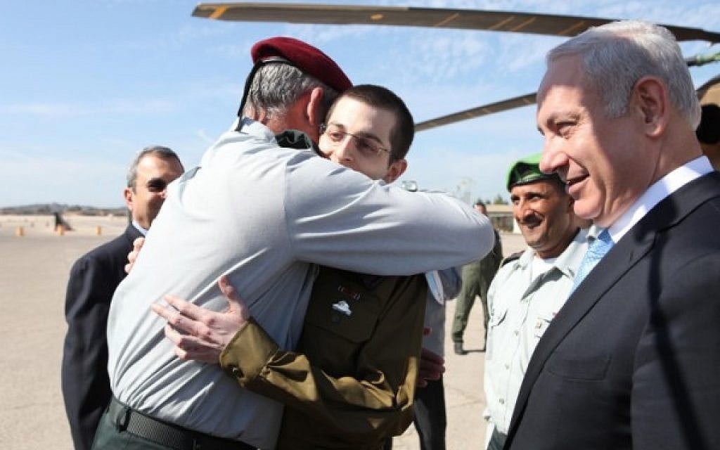 Then-IDF chief Benny Gantz embraces IDF Cpl. Gilad Shalit on the day of his release from Hamas captivity, October 18, 2011, as then-defense minister Ehud Barak and Prime Minister Benjamin Netanyahu look on. (IDF Spokesperson/Flash90)