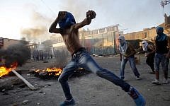 In scenes reminiscent of the first intifada, masked Palestinians throw stones towards Israeli security forces in the Shuafat refugee camp on the outskirts of Jerusalem in September (photo credit: Suliman Khader/Flash90)