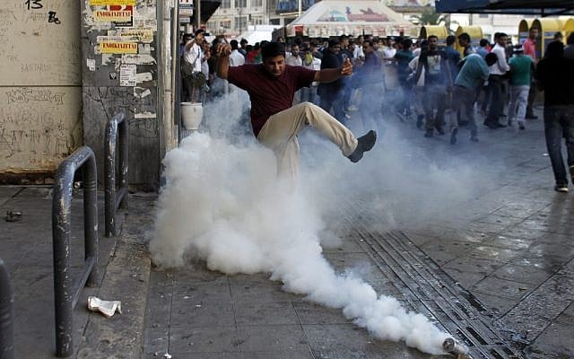 A man tries to kick a tear-gas canister away, as Muslims protest in Athens against a film produced in the U.S. that they say insults the Prophet Muhammad on Sunday. (photo credit: AP/Kostas Tsironis)