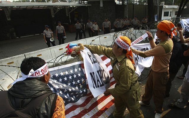 Police officers watch as Muslim protesters hang banners and a US flag on the razor wire surrounding the US Embassy compound in Jakarta, Indonesia, September 19, 2012 (photo credit: AP/Tatan Syuflana)