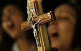 In this Sunday, Oct. 16, 2011 file photo, Egyptian Copts carry a cross and a candle and chant prayers while taking part in a protest marking one week since deadly clashes between Coptic protesters and the military, in Cairo. (photo credit: AP/Nasser Nasser)