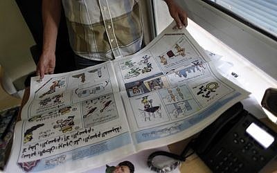 Egyptian cartoonist Khalid Abdul-Ati holds a copy of the Egyptian Al Watan daily newspaper with a two-page spread of cartoons with a headline in Arabic that reads “nothing cracks cartoons but cartoons,” at the newspaper's headquarters in Cairo, Egypt, on Wednesday. (photo credit: AP/Nasser Nasser)