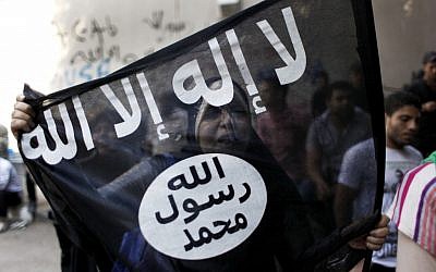 An Egyptian woman holds a black flag with Islamic inscription in Arabic that reads, "No God but Allah, and Mohammed is his prophet," in front of the US Embassy in Cairo, Egypt, on Wednesday, Sept. 12, 2012. (photo credit: Nasser Nasser/AP)