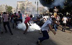 Egyptian protesters run for cover from tear gas during clashes near the US Embassy in Cairo earlier this month (photo credit: AP/Khalil Hamra)