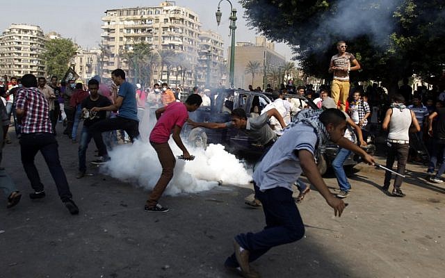 Egyptian protesters run for cover from tear gas during clashes near the US Embassy in Cairo earlier this month (photo credit: AP/Khalil Hamra) Egyptian protesters run for cover from tear gas during clashes near the US Embassy in Cairo earlier this month (photo credit: AP/Khalil Hamra)