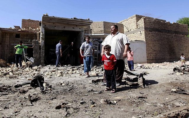 Iraqis stand in rubble at the scene of a car bomb attack in the town of Taji, about 12 miles (20 kilometers) north of Baghdad, Iraq, Sunday, Sept. 30 (photo credit: AP/Hadi Mizban)