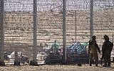 Illustrative: Israeli soldiers stand guard on Tuesday as Eritrean asylum seekers sit on the ground behind a border fence, after they attempted to cross illegally from Egypt into Israel. (AP/Ariel Schalit)