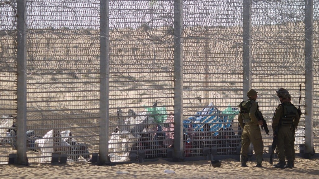 Israeli soldiers stand guard on Tuesday as Eritrean asylum-seekers sit on the ground behind a border fence, after they attempted to cross illegally from Egypt into Israel. (photo credit: AP/Ariel Schalit) Israeli soldiers stand guard on Tuesday as Eritrean asylum-seekers sit on the ground behind a border fence, after they attempted to cross illegally from Egypt into Israel. (photo credit: AP/Ariel Schalit)
