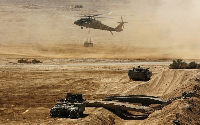 An Israeli helicopter flies above armored vehicles during an army exercise at the Shizafon Army Base in southern Israel. (photo credit: Tara Todras-Whitehill/AP)