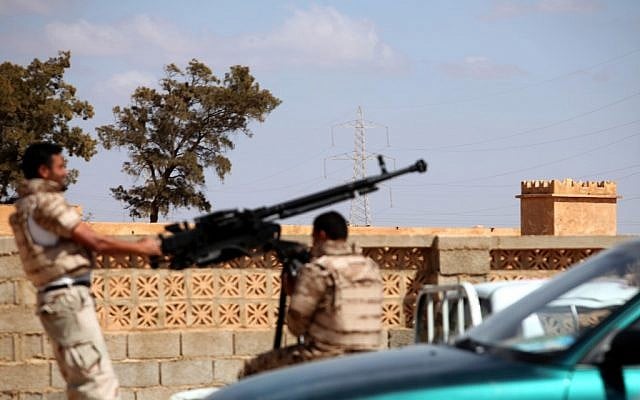 Libyan National Army soldiers in Benghazi prepare to enter Rafallah al-Sahati Islamic Militia Brigades compound, seen behind the wall. (photo credit: AP/Mohammad Hannon)