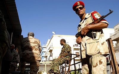 Libyan security forces stand guard as people turn in weapons in Benghazi, Libya, Saturday. (photo credit: AP)