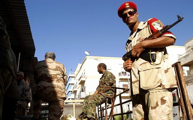 Libyan security forces stand guard as people turn in weapons in Benghazi, Libya, Saturday. (photo credit: AP)