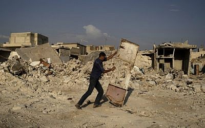 A Syrian man pushes a door away from the rubble of houses destroyed in a government airstrike in an outskirt of Aleppo on Friday (AP Photo/Muhammed Muheisen)