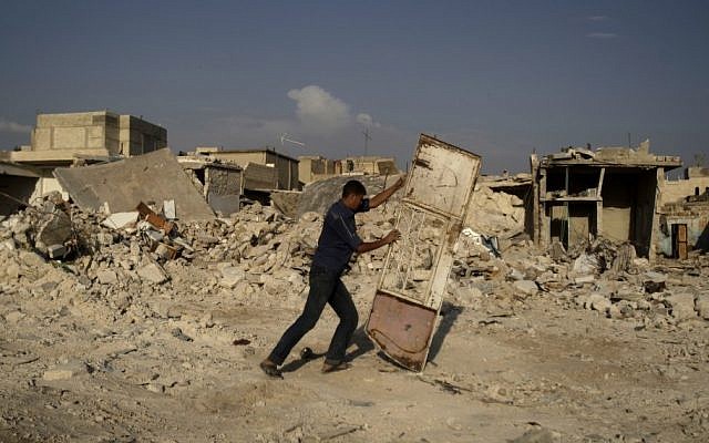 A Syrian man pushes a door away from the rubble of houses destroyed in a government airstrike in an outskirt of Aleppo on Friday (AP Photo/Muhammed Muheisen)