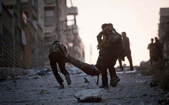 Rebel soldiers help a severely wounded colleague after he was shot by a Syrian Army sniper in the Izaa district of Aleppo on Saturday (photo credit: AP/Manu Brabo)
