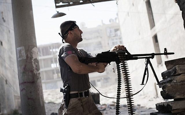A Free Syrian Army fighter fires at Syrian Army positions (photo credit: AP/Manu Brabo)